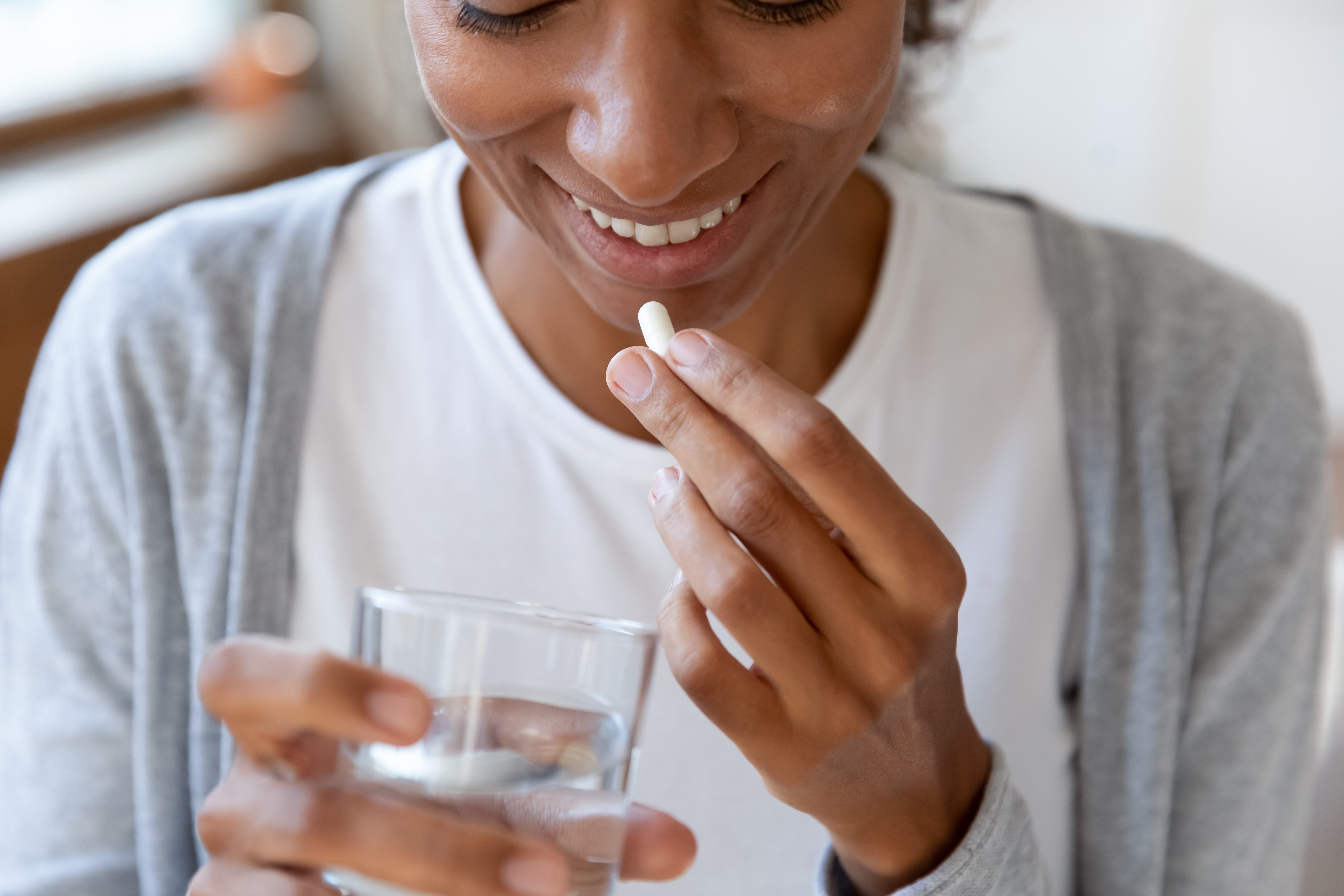 Black woman taking pill while smiling